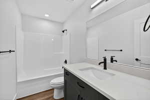 Bathroom featuring shower / tub combination, vanity, and dark wood-style flooring