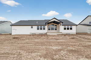 Rear view of house featuring a shingled roof and a patio area