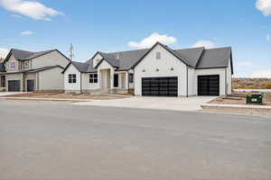 Modern farmhouse with board and batten siding, a shingled roof, driveway, and an attached garage