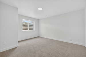 Unfurnished room featuring light carpet and baseboards