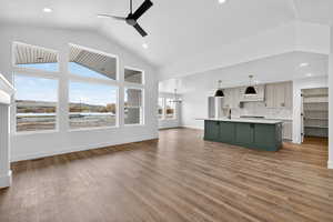 Unfurnished living room with light wood-type flooring, a chandelier, ceiling fan, recessed lighting, and high vaulted ceiling