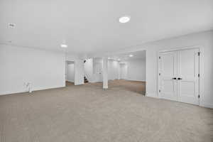 Finished below grade area with stairway, light colored carpet, and recessed lighting