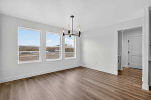 Unfurnished dining area with a chandelier and light wood-style floors