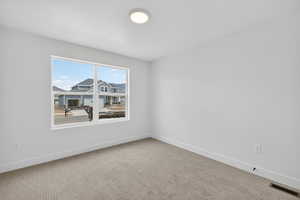 Carpeted spare room featuring baseboards
