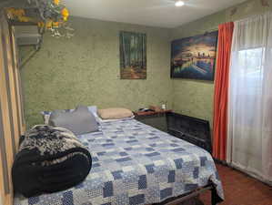 Bedroom featuring dark wood-style flooring and wallpapered walls