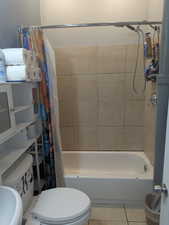 Full bath featuring shower / bathtub combination with curtain, tile patterned flooring, and a textured wall