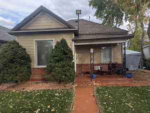 View of front of property featuring a front yard, a porch, roof with shingles, and brick siding