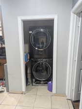 Laundry room with light tile patterned floors and stacked washer / dryer