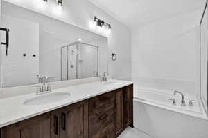 Full bathroom with a shower stall, double vanity, and a garden tub