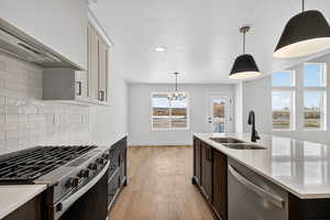 Kitchen with appliances with stainless steel finishes, hanging light fixtures, custom exhaust hood, light stone countertops, and a textured ceiling