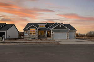 Craftsman house featuring stone siding, board and batten siding, an attached garage, and a shingled roof