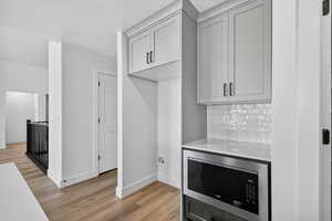 Detailed view of stainless steel microwave, wood finished floors, and tasteful backsplash