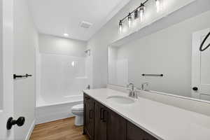 Bathroom with vanity, shower / bath combination, and light wood-type flooring