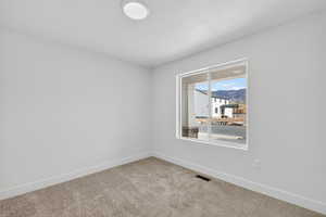 Carpeted empty room featuring baseboards and a mountain view