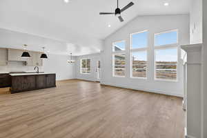 Unfurnished living room featuring high vaulted ceiling, a chandelier, recessed lighting, light wood-type flooring, and a ceiling fan