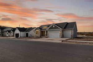 View of front of house featuring a garage, board and batten siding, concrete driveway, stone siding, and roof with shingles