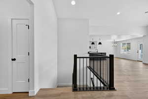 Hallway with an upstairs landing, light wood-type flooring, recessed lighting, and a chandelier