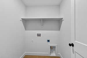 Washroom with hookup for an electric dryer, wood finished floors, and hookup for a washing machine