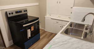 Kitchen with stainless steel electric range, white cabinets, dark wood finished floors, and light countertops