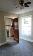 Spare room with carpet flooring, a ceiling fan, and a fireplace