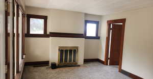 Unfurnished living room with carpet floors and a brick fireplace