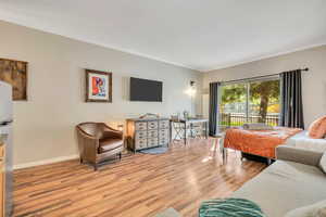 Bedroom featuring light wood-style floors, ornamental molding, access to exterior, and stainless steel fridge