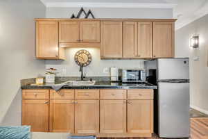 Kitchen with crown molding, appliances with stainless steel finishes, light wood-type flooring, and tile countertops