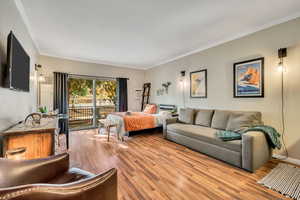 Bedroom with access to exterior, crown molding, and light wood-style floors