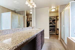 Bathroom featuring a walk in closet, a shower stall, light tile patterned flooring, and vanity