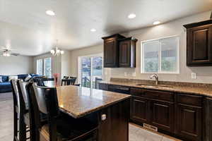 Kitchen with a kitchen breakfast bar, dark brown cabinets, open floor plan, a kitchen island, and dark stone countertops