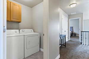 Washroom with washing machine and dryer, cabinet space, and light carpet