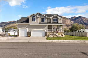 Traditional home featuring a porch, stucco siding, a mountain view, driveway, and brick siding
