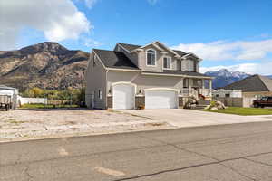 Traditional home with a mountain view, stucco siding, concrete driveway, a garage, and brick siding