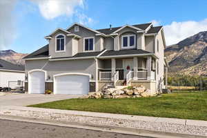 View of front facade featuring a mountain view, covered porch, stucco siding, and driveway