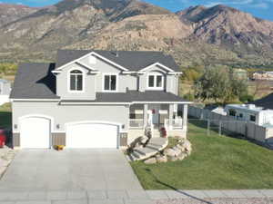 View of front of home featuring stucco siding, a mountain view, concrete driveway, and covered porch