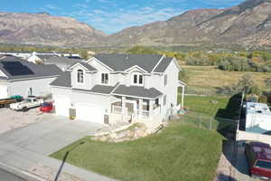 Traditional-style home with a porch, stucco siding, roof with shingles, a mountain view, and concrete driveway