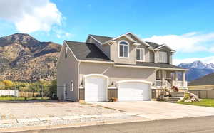 View of front of property featuring a mountain view, a porch, driveway, stucco siding, and an attached garage