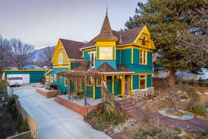 Victorian home with a shingled roof, a porch, a mountain view, and stone siding