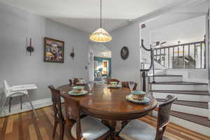 Dining area featuring wood finished floors, stairs, and a ceiling fan