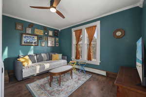 Living area with ornamental molding, a baseboard heating unit, dark wood-style floors, and a ceiling fan