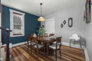Dining room with stairs and dark wood-style floors