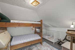 Bedroom with a textured ceiling, lofted ceiling, and carpet