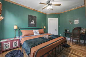 Bedroom with wood finished floors, a ceiling fan, and ornamental molding