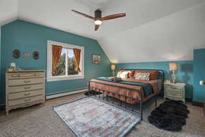 Carpeted bedroom with vaulted ceiling, a baseboard heating unit, and ceiling fan