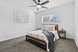 Carpeted bedroom featuring ceiling fan and baseboards