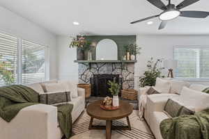 Living area featuring a stone fireplace, recessed lighting, and ceiling fan