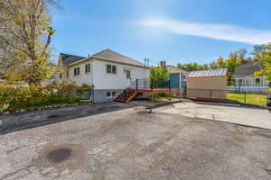 Rear view of property with roof with shingles, stairway, a patio, a wooden deck, and a storage unit