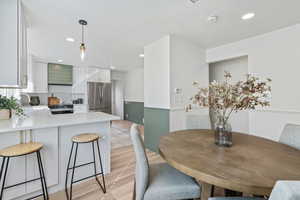 Dining room featuring a wainscoted wall, light wood-style flooring, and recessed lighting