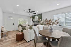 Dining room with a stone fireplace, recessed lighting, light wood finished floors, and a ceiling fan