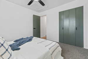 Bedroom with attic access, carpet flooring, a ceiling fan, and a closet